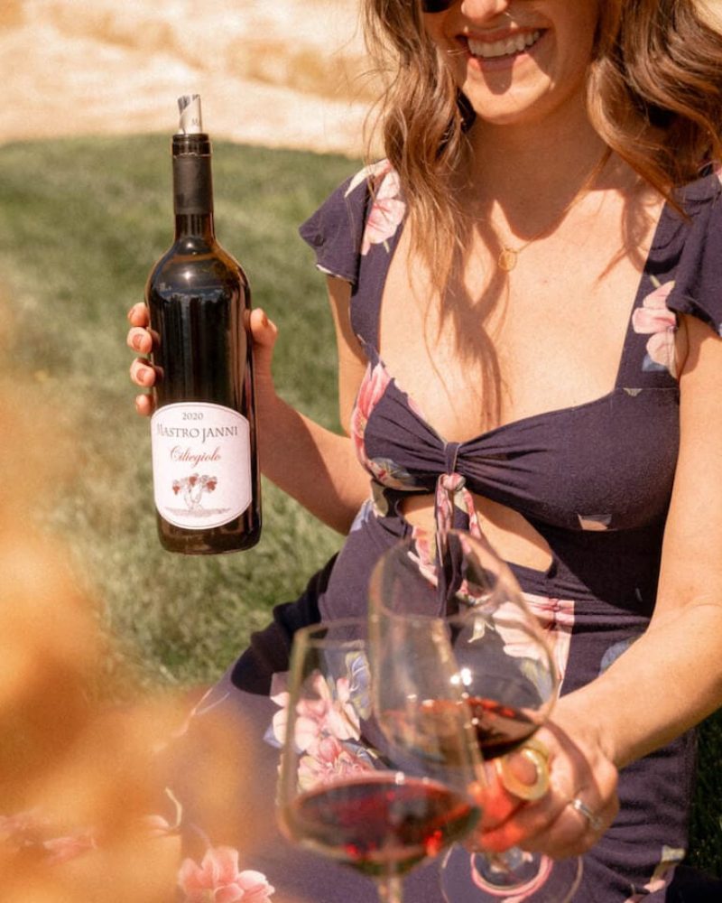 ragazza sorridente che versa vino rosso